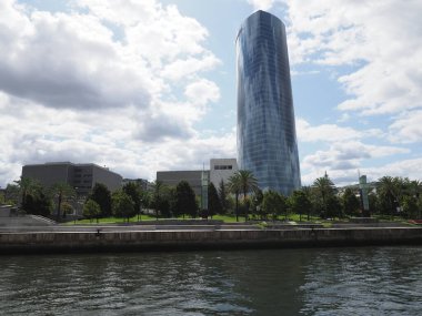 İspanya 'nın Biscay eyaletindeki Avrupa' nın BILBAO şehrinde Nervion Nehri ve Iberdrola Kulesi, 2019 yılının güneşli yaz gününde bulutlu mavi gökyüzü.
