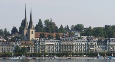 LUCERNE, SWitzERLAND - 6 Ağustos 2018: Avrupa 'daki St. Leodegar tarihi otel ve kilisesi, ılık güneşli yaz gününde açık mavi gökyüzü.