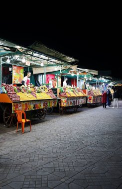 MARRAKESH, MOROCCO - 25 JANUARY 2023: Scenic food souks on Jemaa el-Fnaa in African city at evening winter day - vertical clipart