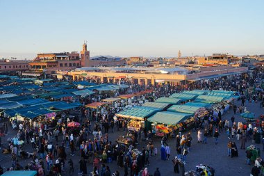 MARRAKESH, MOROCCO - 28 HAZİRAN 2023: Afrika şehrinin Medine 'sinde Jemaa el-Fnaa' da manzaralı çarşılar, ılık güneşli kış gününde açık mavi gökyüzü.
