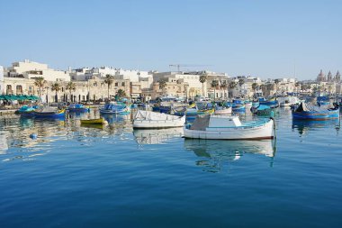 MARSAXLOKK, MALTA Mayıs 2022: Avrupa köyündeki balıkçı tekneleriyle limana bakın, ılık güneşli bahar gününde açık mavi gökyüzü.