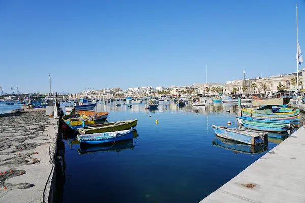 MARSAXLOKK, MALTA - 17 Mayıs 2022: Malta 'daki Avrupa köyünde liman, ılık güneşli bahar gününde açık mavi gökyüzü.