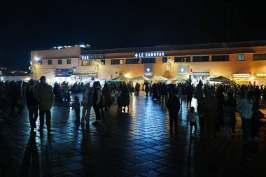 MARRAKESH, MOROCCO - 25 JANUARY 2023: People on Jemaa el-Fnaa in African city at evening winter day. clipart