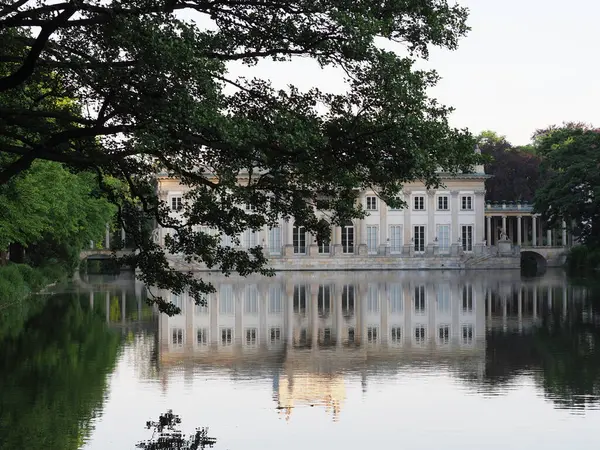 stock image Reflection of palace on isle at lake in baths park, European Warsaw capital city, Poland in Masovian, cloudy sky in 2019 warm sunny spring day on June