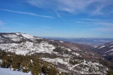 Polonya 'nın Avrupa Szczyrk kenti yakınlarındaki Silesian Beskid' de beyaz yamaç, 2022 yılının soğuk ve güneşli kış gününde açık mavi gökyüzü.