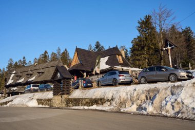 SZCZYRK, POLAND - 19 Mart 2022: Silesian Beskid Dağları 'ndaki ahşap han Avrupa Bialy Krzyz, açık mavi gökyüzü soğuk kış gününde.