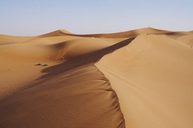 Afrika 'nın güneydoğusundaki Sahra Çölü' nde muhteşem Erg Chigaga kum tepesi, 2023 yılının sıcak ve güneşli kış gününde açık mavi gökyüzü..