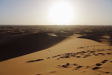Afrika 'nın güneydoğu MoroCCO' daki Sahra Çölü 'ndeki Erg Chigaga tepesinde güneş batıyor. 2023' te açık mavi gökyüzü Ocak ayında güneşli ve güneşli bir kış günü..