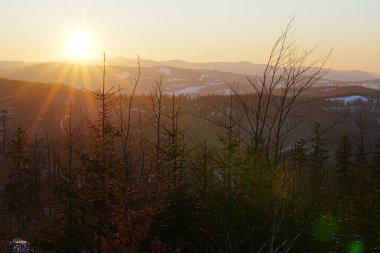 Polonya 'daki Szczyrk' te Avrupa Bialy Krzyz yakınlarındaki Silesian Beskid 'in üzerinde güneş batarken, 2022 yılının soğuk ve güneşli kış gününde açık mavi gökyüzü.