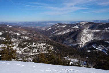 Polonya 'nın Avrupa Szczyrk kenti yakınlarındaki Silesian Beskid' deki karlı vadi, 2022 yılının soğuk ve güneşli kış gününde açık mavi gökyüzü.