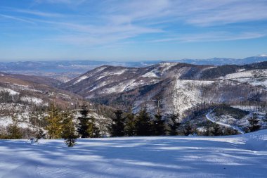 Polonya 'nın Avrupa Szczyrk kenti yakınlarındaki Silesian Beskid' te beyaz manzara, 2022 yılının soğuk ve güneşli kış gününde açık mavi gökyüzü.