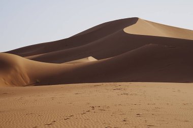 Afrika 'nın güneydoğusundaki Sahra Çölü' nde muhteşem Erg Chigaga kum tepesi, 2023 yılının sıcak ve güneşli kış gününde açık mavi gökyüzü..