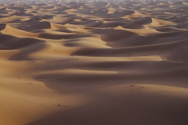 Afrika 'nın güneydoğusundaki Sahra Çölü' nde Erg Chigaga kum oluşumları denizi 2023 yılının sıcak kış gününde açık mavi gökyüzü..