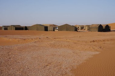 Afrika 'nın güneydoğusundaki Sahra Çölü' nde Erg Chigaga yakınlarındaki çadır kampı, Ocak 2023 'te güneşli bir kış günü açık mavi gökyüzü..