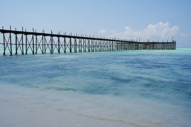 Tanzanya 'daki Afrika Zanzibar Adası' ndaki Hint Okyanusu 'ndaki Jambiani sahilindeki ahşap iskele 2024' te güneşli bir yaz gününde açık mavi gökyüzü..