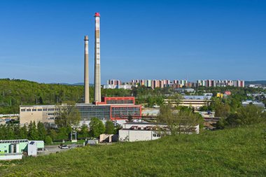 Güneşli bir sabahta arka planda konut binaları olan sanayi binaları ve bacalarla manzara