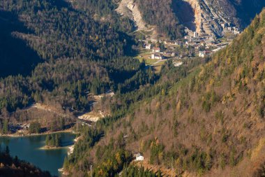 View over autumn-colored mountains to the Lago del Predil and the old mine town Cave del Predil in the Julian Alps clipart