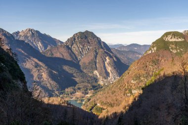 View over autumn-colored mountains to the Lago del Predil and the old mine town Cave del Predil in the Julian Alps clipart