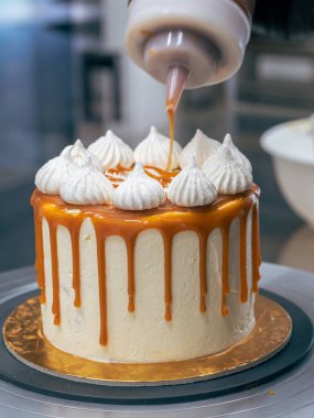 Profesyonel fırıncı çikolatalı ve kremalı pastayı tuzlu karamel ile süslüyor.