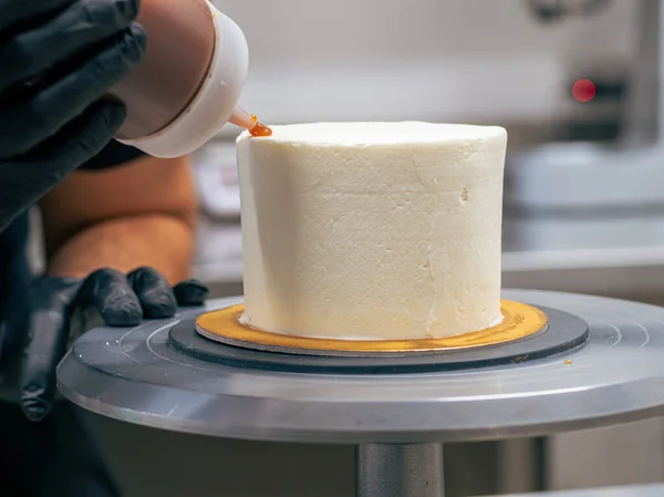 stock image professional baker decorating a chocolate and cream cake with salty caramel