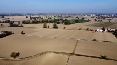 Eski çiftlikler ve güneş enerjisi panelleri arasında kırsal yolda giden mavi arabanın havadan görünüşü
