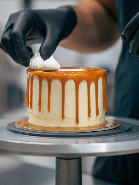 stock image professional baker decorating a chocolate and cream cake with salty caramel