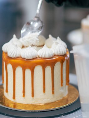 Profesyonel fırıncı çikolatalı ve kremalı pastayı tuzlu karamel ile süslüyor.