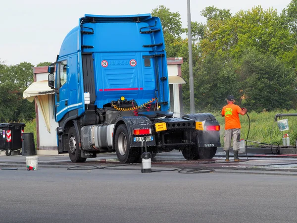 stock image Man spraying exterior of blue semi truck using self service equipment at car wash.