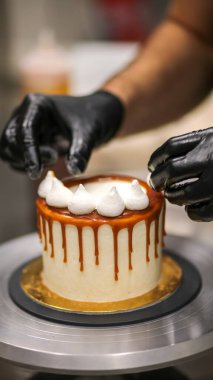 Şef kremalı pastanın üstünü dekore ediyor.