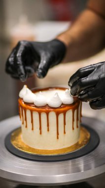 Şef kremalı pastanın üstünü dekore ediyor.