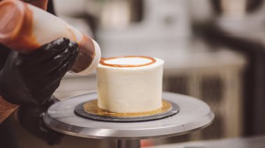 Şef kremalı pastanın üstünü dekore ediyor.