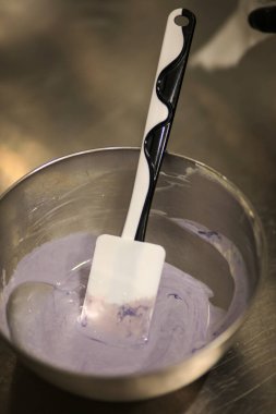 Şef, profesyonel mutfak laboratuarında leylak kremalı pasta yapıyor.