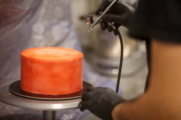 stock image cook preparing a red frosted cake using air bush