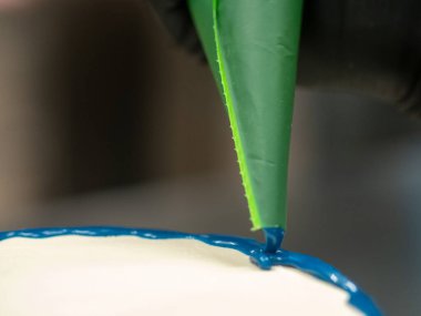 Pasta şefi pasta tasarımcısı mutfak laboratuarında mavi beyaz peynirli kek hazırlıyor.