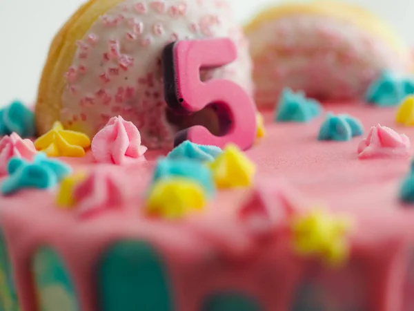 stock image Close up of pink frosted dripping cake with donut and plastel brushed royal star sprinkles insolated on white studio shot