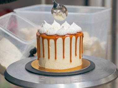 Profesyonel fırıncı çikolatalı ve kremalı pastayı tuzlu karamel ile süslüyor.