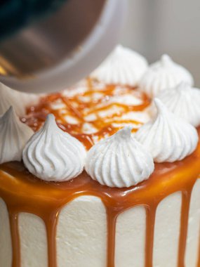 Profesyonel fırıncı çikolatalı ve kremalı pastayı tuzlu karamel ile süslüyor.