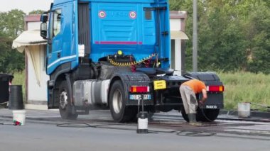 Adam, oto yıkamacıdaki self servis ekipmanlarını kullanarak mavi kamyonun dışını spreyliyor..