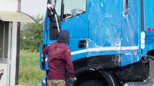在洗车时使用自助设备喷涂蓝色半卡车外部的男子 — 图库视频影像