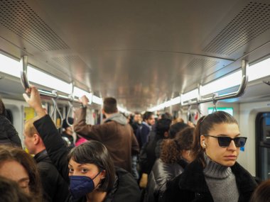 Milano, İtalya - Kasım 2022 Yüzü maskeli ya da maskesiz yeraltı metrosunda seyahat