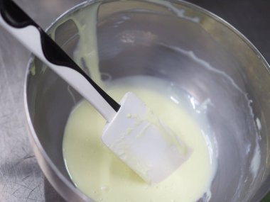 Pasta şefi pipo poşetini karıştırıyor. Renk derecelendirme için yenebilir turkuaz boyayla karıştırılıyor.