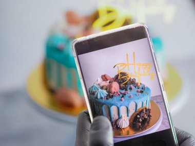 Donutlar, kremalı krema, turkuaz pasta, doğum günü kutlaması için akıllı telefon fotoğrafçılığı.