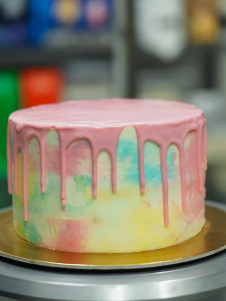 色のグレーディングを滴下するための食用ピンク塗料で満たされたペースト状のシェフ職人の絞る配管バッグは 虹のパステルケーキを焼き — ストック写真