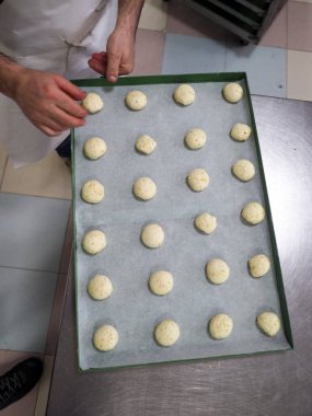 Fırıncı şefi kırmızı menekşe sarısı ve yeşil küçük küçük 30 gramlık renkli çörekler yapıyor.