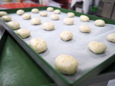 Fırıncı şefi kırmızı menekşe sarısı ve yeşil küçük küçük 30 gramlık renkli çörekler yapıyor.