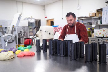 Profesyonel kalıpları renkli hamurla dolduran fırıncı kalp ve yıldız şeklinde ekmek hazırlıyor.