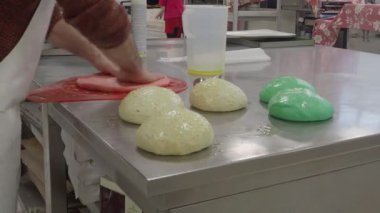 Yaratıcı fırıncı masaj yapıyor, pürüzsüz masaj yapıyor ekmek için renkli hamurlar kesiyor, pizza Focaccia ve yemek servisi için çörekler ve aperatif.