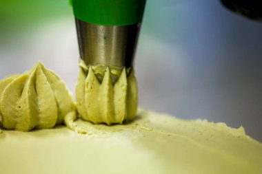 Pasta şefi kremalı helezon fıstıklı girdaplar yapıyor katmanlı yeşil çikolatalı pasta