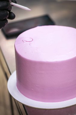 Pasta tasarımcısının üstünde mor kremalı pasta eli beyaz kremayla duygusal pişmanlık mesajı yazıyor.