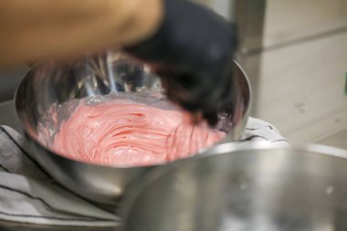 Pasta şefi doğum günü pastası için beyaz çikolata pembesi dolgusu hazırlıyor. kek dekorasyonu